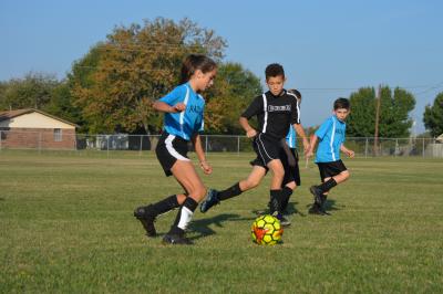 Boy and Girl soccer players going for the ball