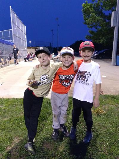 Three youth baseball players in different uniforms.